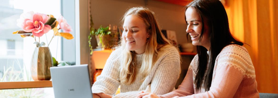 to kvinnelige studenter ser sammen på en laptop. 