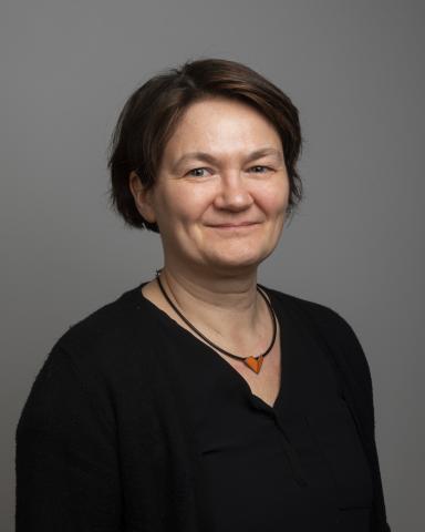 Kvinne med sort genser ser i kamera.