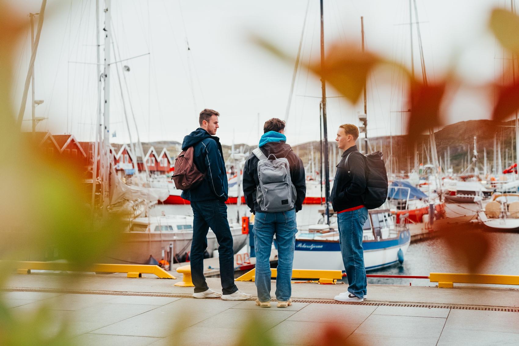 Tre studenter står ved en brygge. Foto.