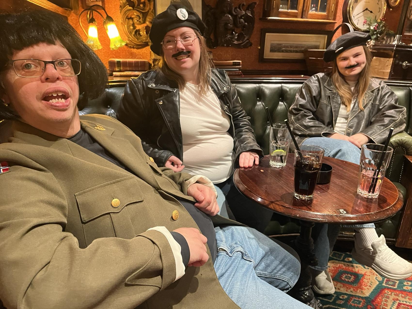 tre personer i en bar med kostymer